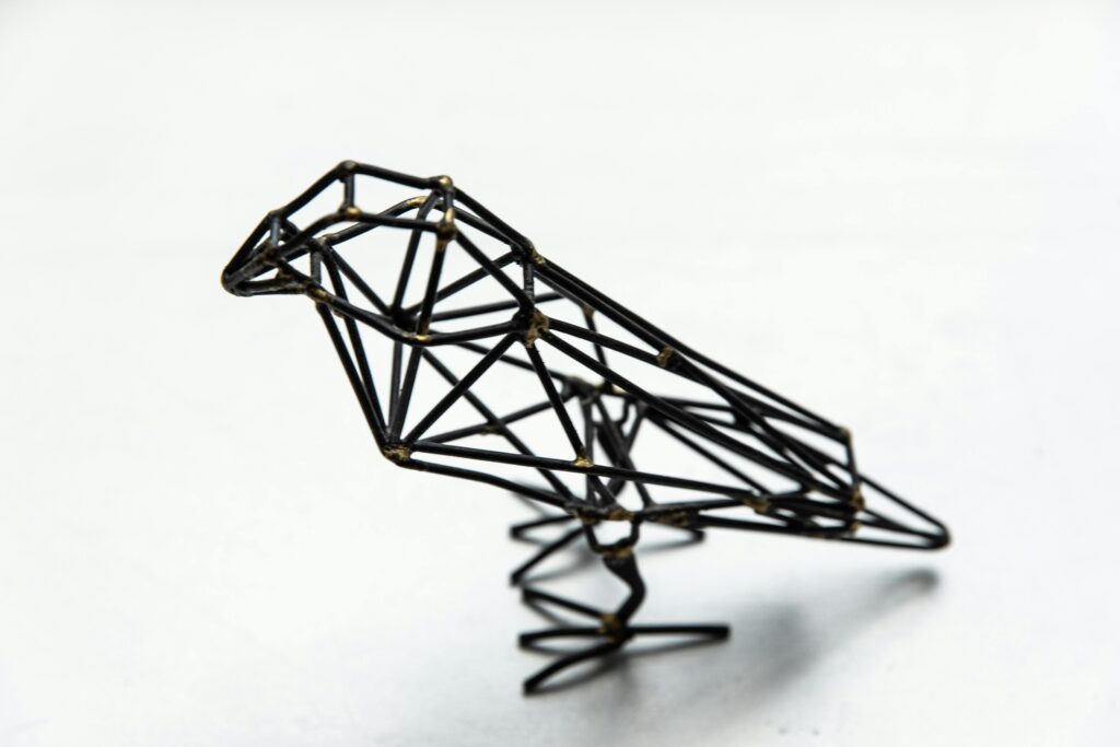 Minimalist metal bird sculpture with geometric design on a clean white background, perfect for modern decor.